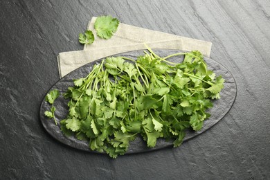 Photo of Fresh coriander on dark gray textured table, top view