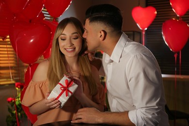 Photo of Lovely couple with gift in room. Valentine's day celebration