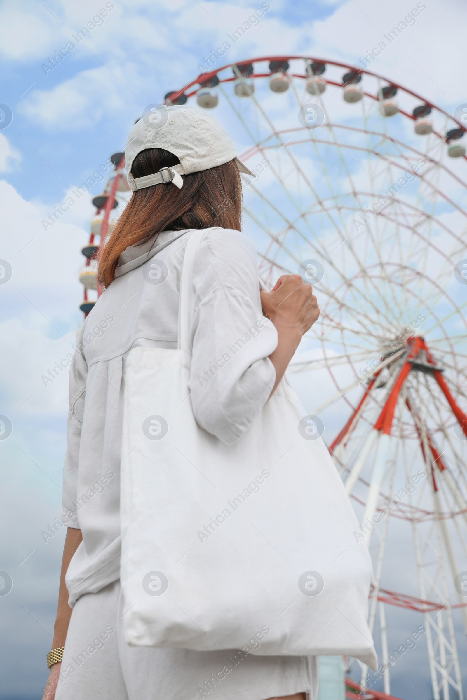 Photo of Young woman near Ferris wheel outdoors, back view