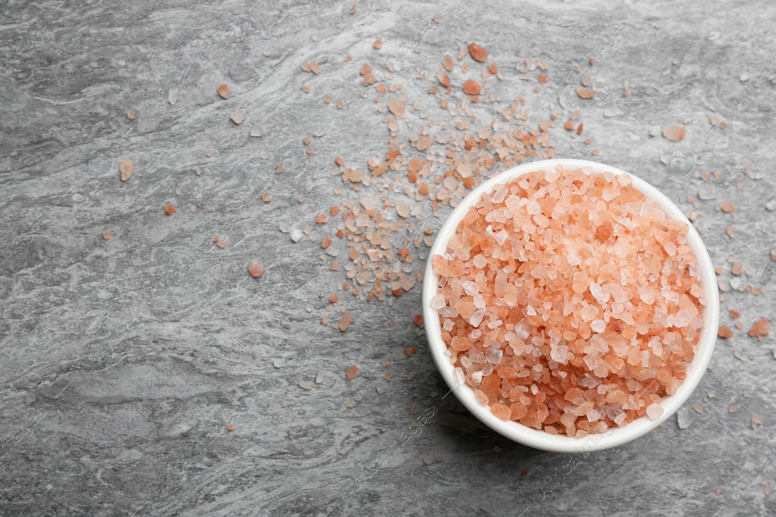 Photo of Pink himalayan salt on grey table, top view. Space for text