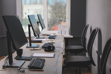 Photo of Open office interior. Modern workplaces with computers near window