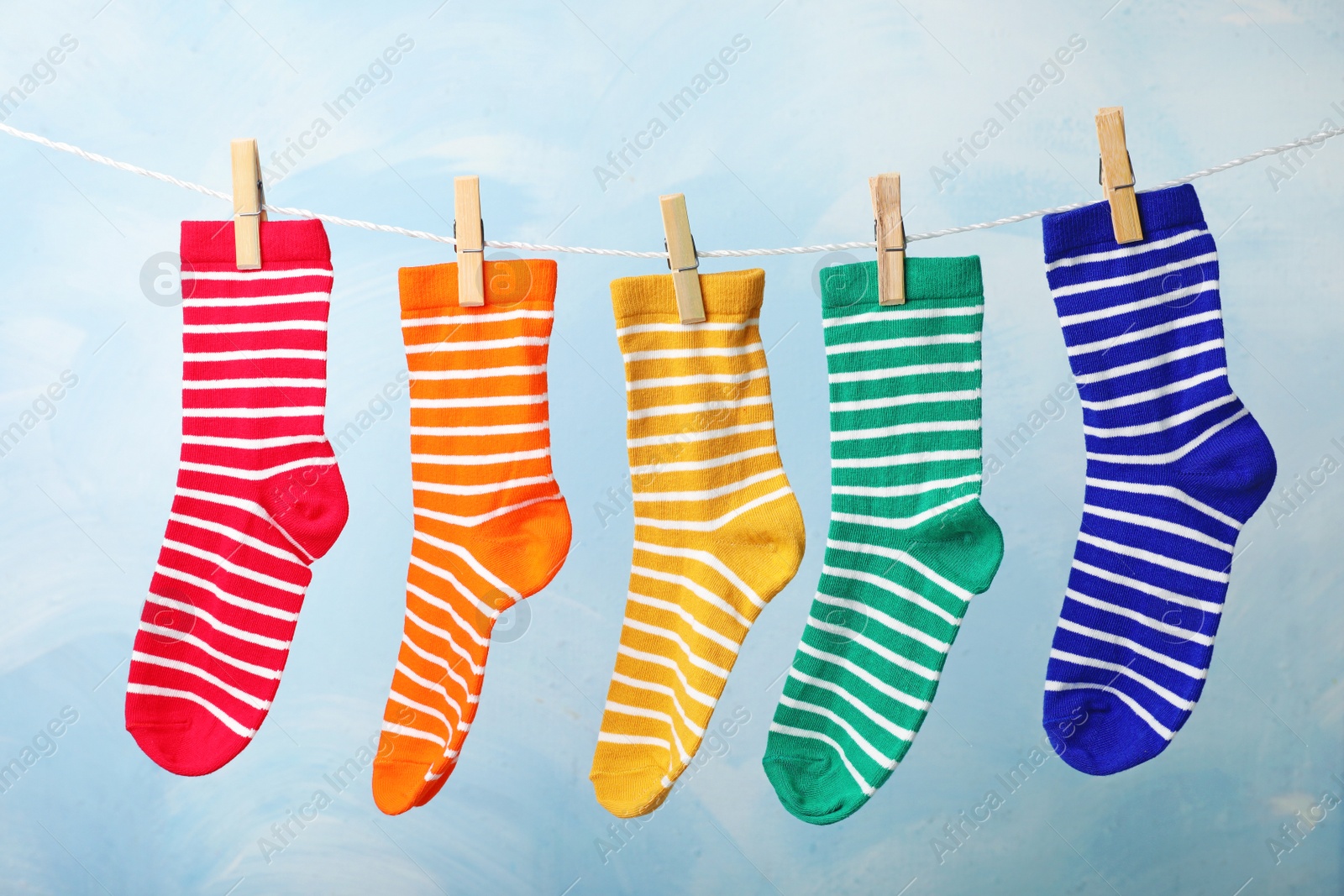 Photo of Cute child socks on laundry line against color background