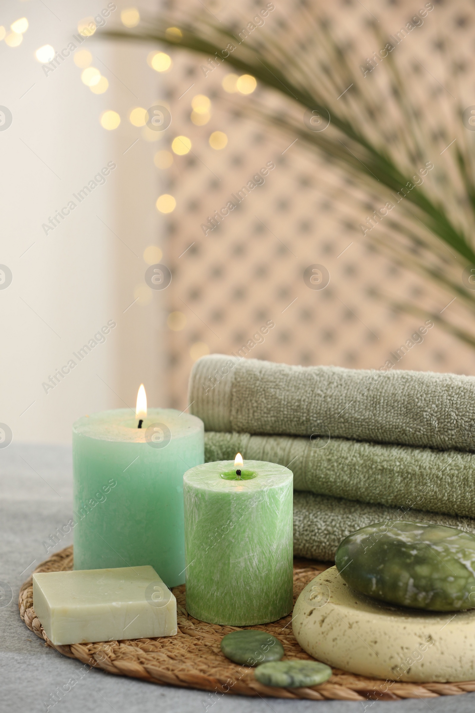 Photo of Spa composition. Burning candles, stones, soap and towels on grey table