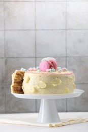 Delicious cake decorated with macarons and marshmallows on white table against tiled background, space for text