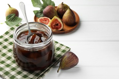 Jar of tasty sweet jam and fresh figs on white wooden table. Space for text