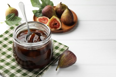 Photo of Jar of tasty sweet jam and fresh figs on white wooden table. Space for text