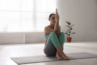 Photo of Woman practicing eagle asana in yoga studio. Garudasana pose