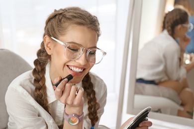 Photo of Portrait of beautiful woman applying makeup indoors