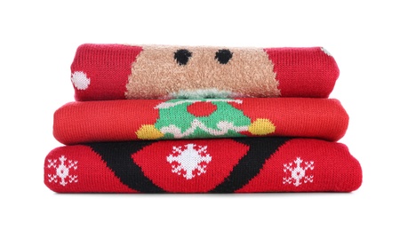 Photo of Stack of warm Christmas sweaters isolated on white