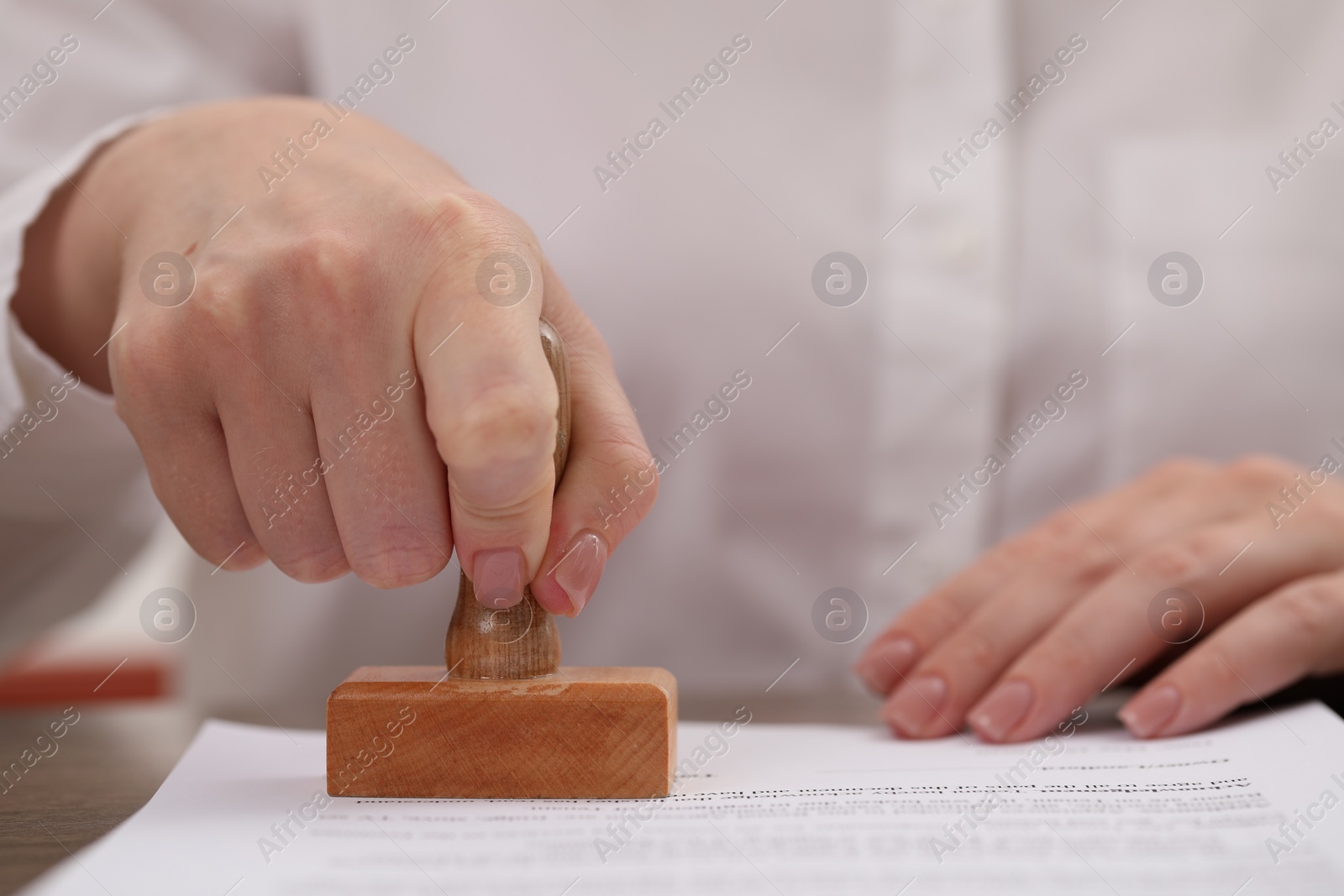 Photo of Woman stamping document at table, closeup view