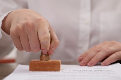 Woman stamping document at table, closeup view