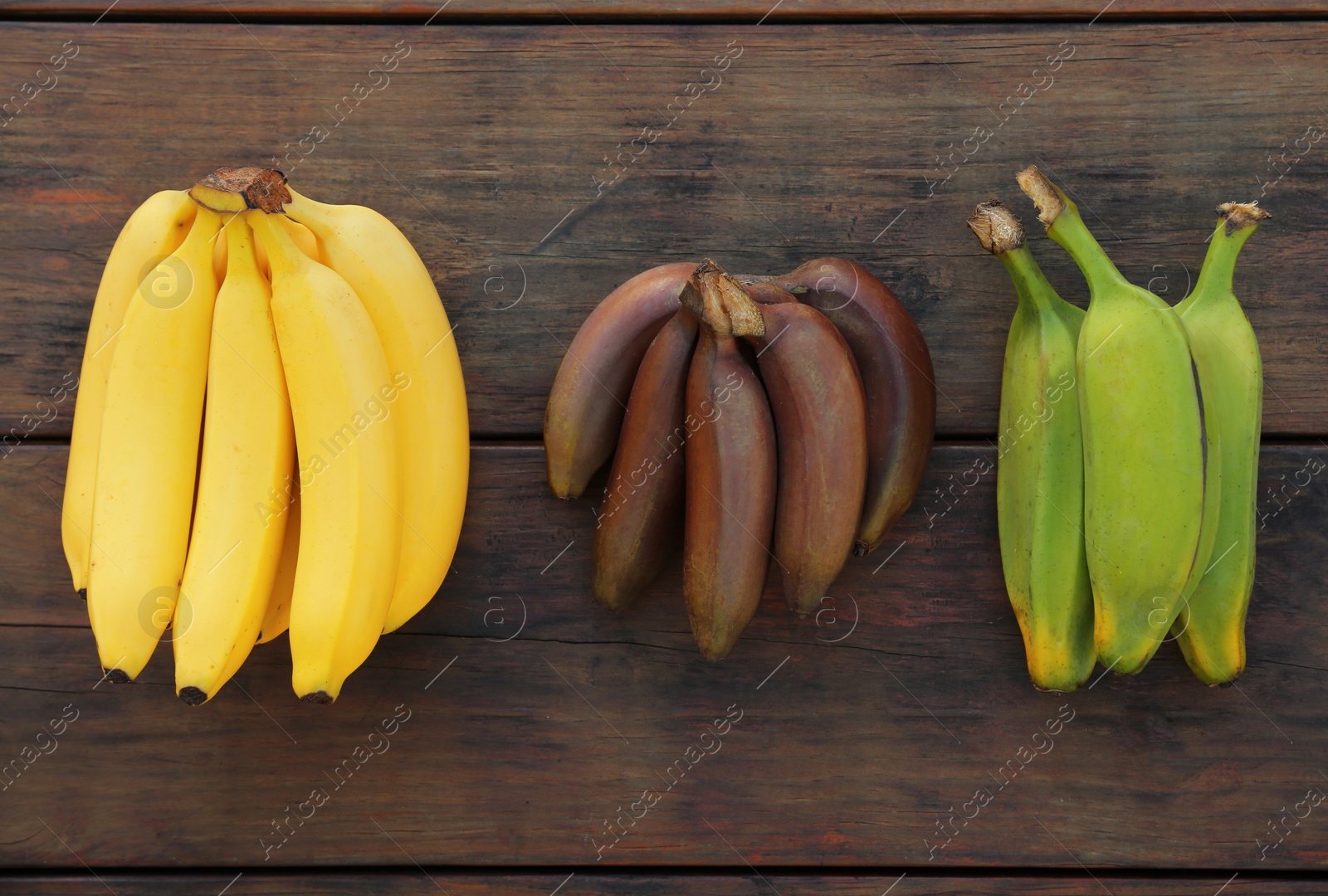 Photo of Different types of bananas on wooden table, flat lay