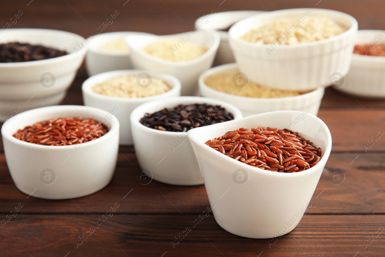 Photo of Bowls with different types of rice on wooden table