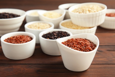 Bowls with different types of rice on wooden table