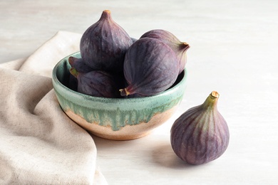 Photo of Bowl with fresh ripe figs on light background. Tropical fruit