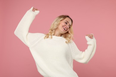 Photo of Happy woman in stylish warm sweater on pink background