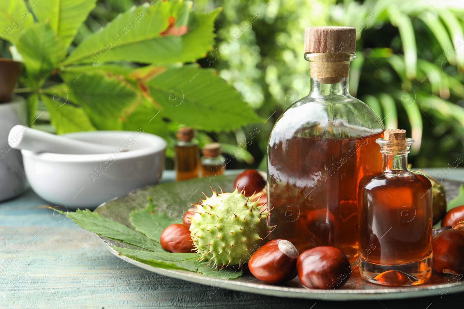 Photo of Chestnuts and bottles of essential oil on table against blurred background