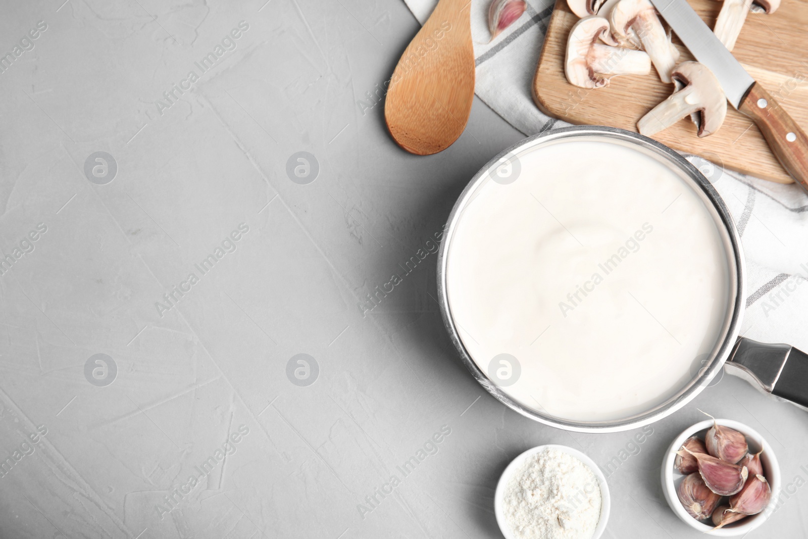 Photo of Flat lay composition with delicious creamy sauce on grey table. Space for text