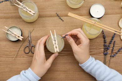 Photo of Woman making aromatic candles at wooden table, top view