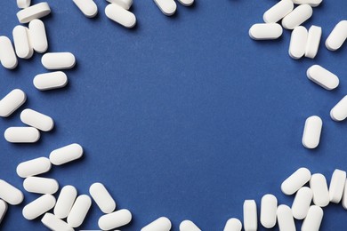 Photo of Vitamin pills on blue background, flat lay. Space for text