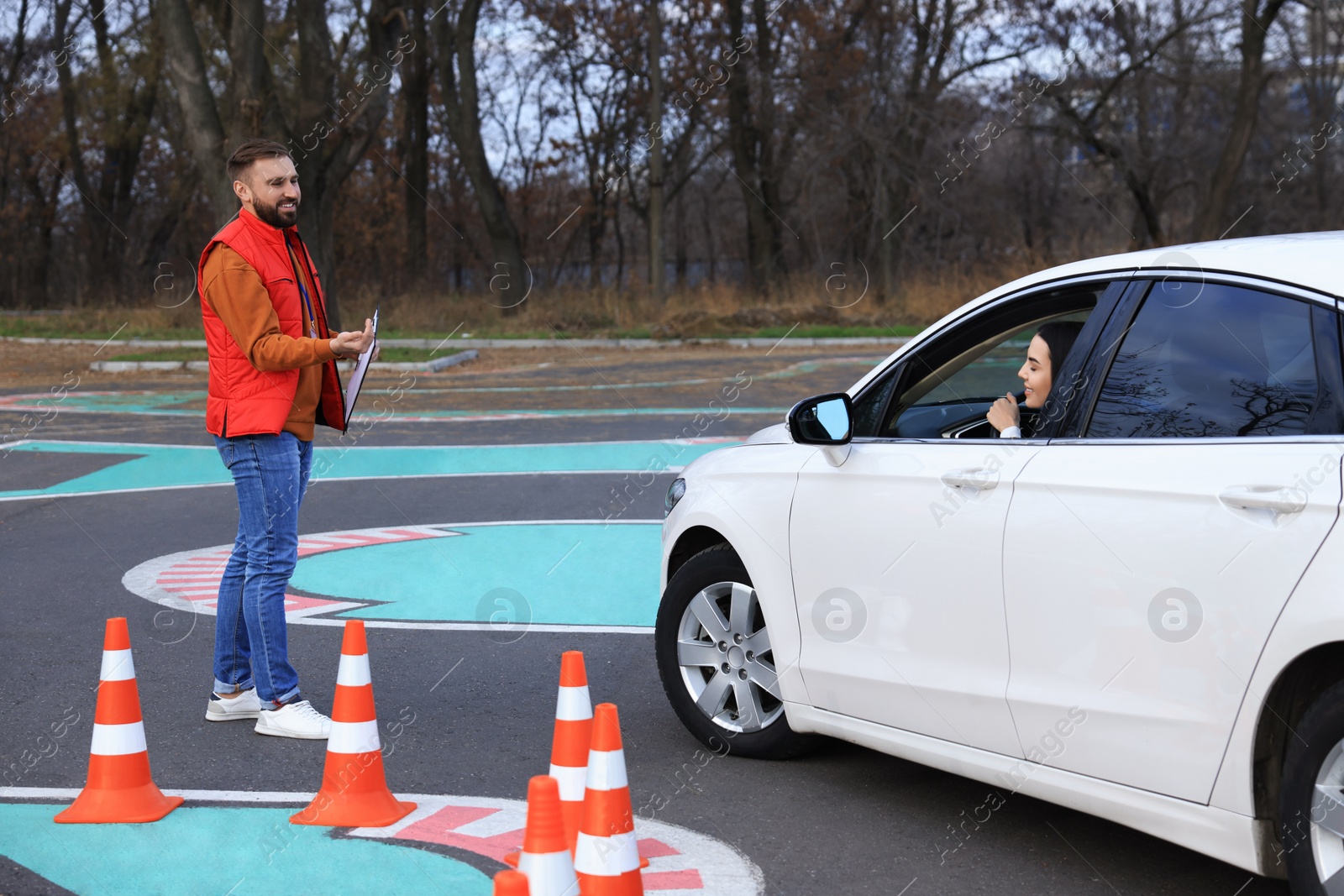 Photo of Instructor near car with his student during exam at driving school test track