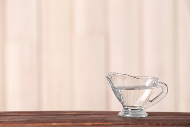 Gravy boat with vinegar on wooden table. Space for text