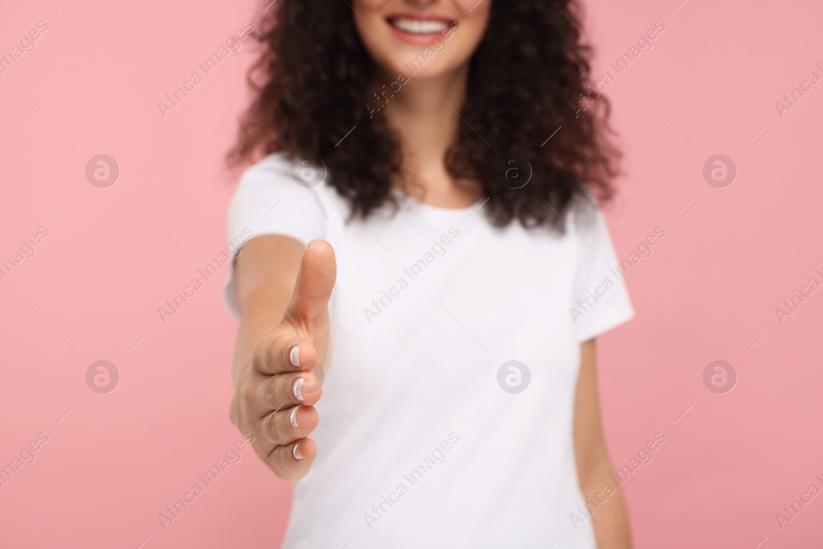 Photo of Woman welcoming and offering handshake on pink background, closeup