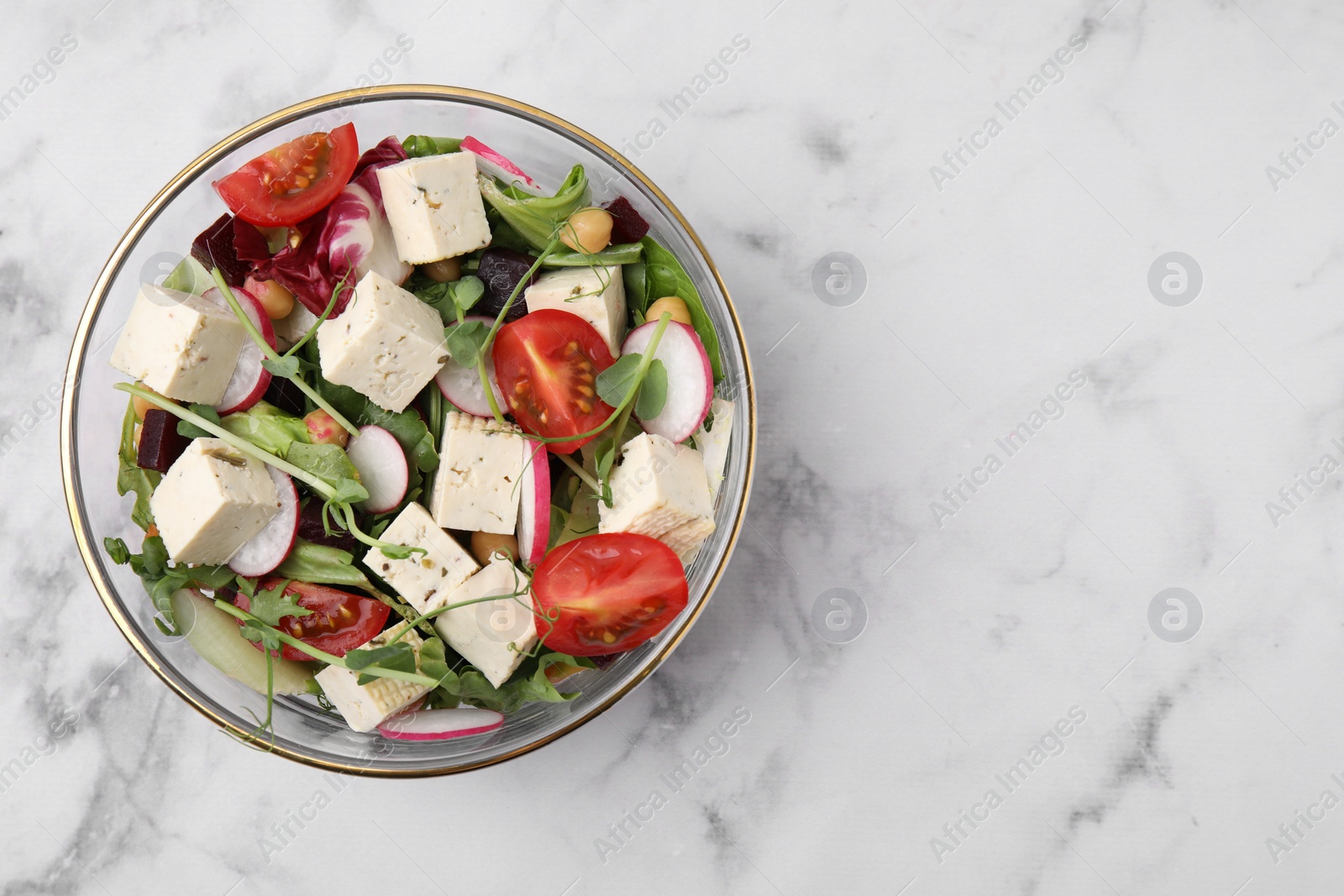 Photo of Bowl of tasty salad with tofu and vegetables on white marble table, top view. Space for text