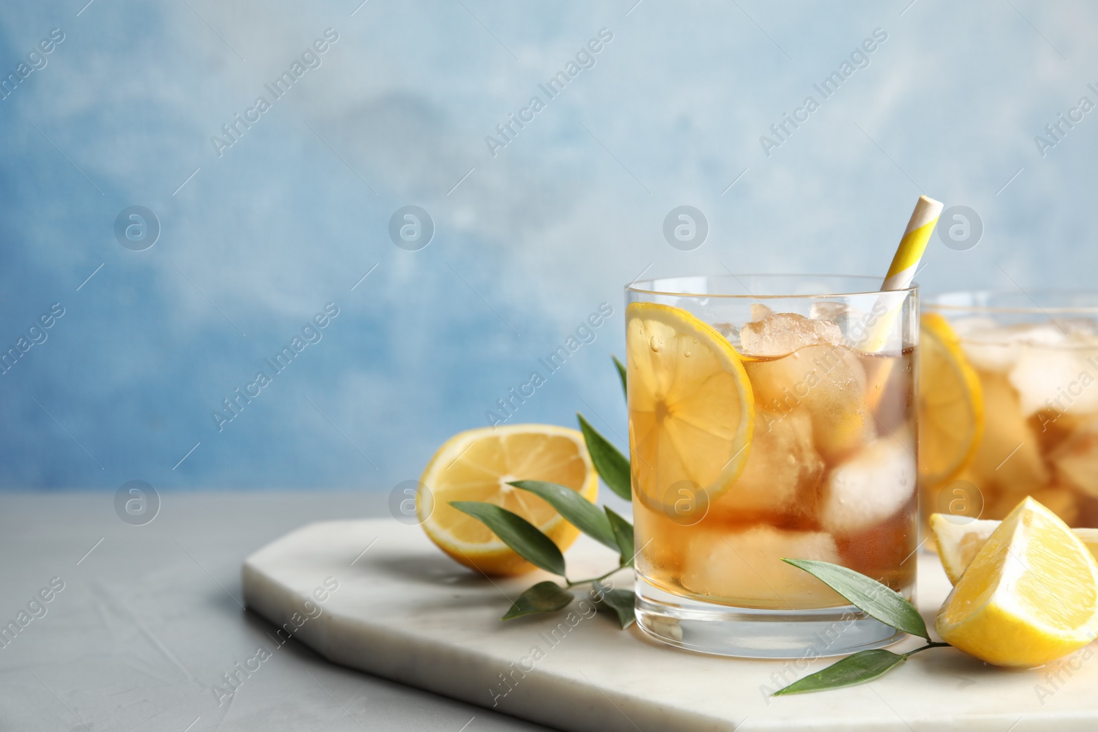 Photo of Glass of lemonade with ice cubes and fruit on table against color background. Space for text