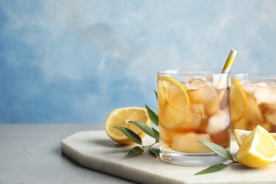 Photo of Glass of lemonade with ice cubes and fruit on table against color background. Space for text