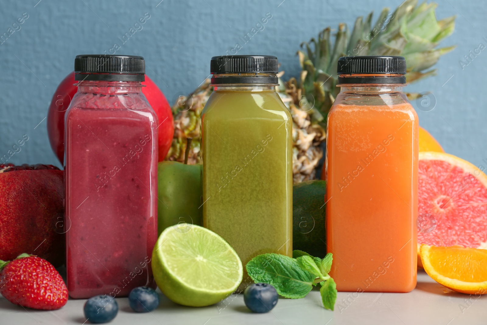 Photo of Bottles with healthy detox smoothies and ingredients on table