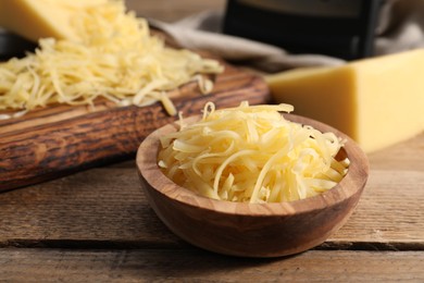 Photo of Grated cheese in bowl on wooden table, closeup