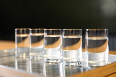 Photo of Shots of vodka on bar counter against dark background, closeup