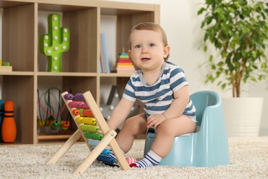 Photo of Little child with abacus sitting on plastic baby potty indoors