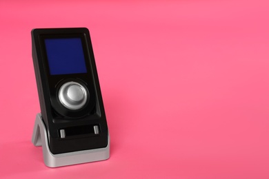 Photo of Modern remote for audio speakers on pink background, space for text