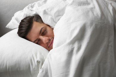 Photo of Handsome man sleeping under soft blanket in bed at home