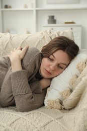 Photo of Sad young woman lying on sofa at home