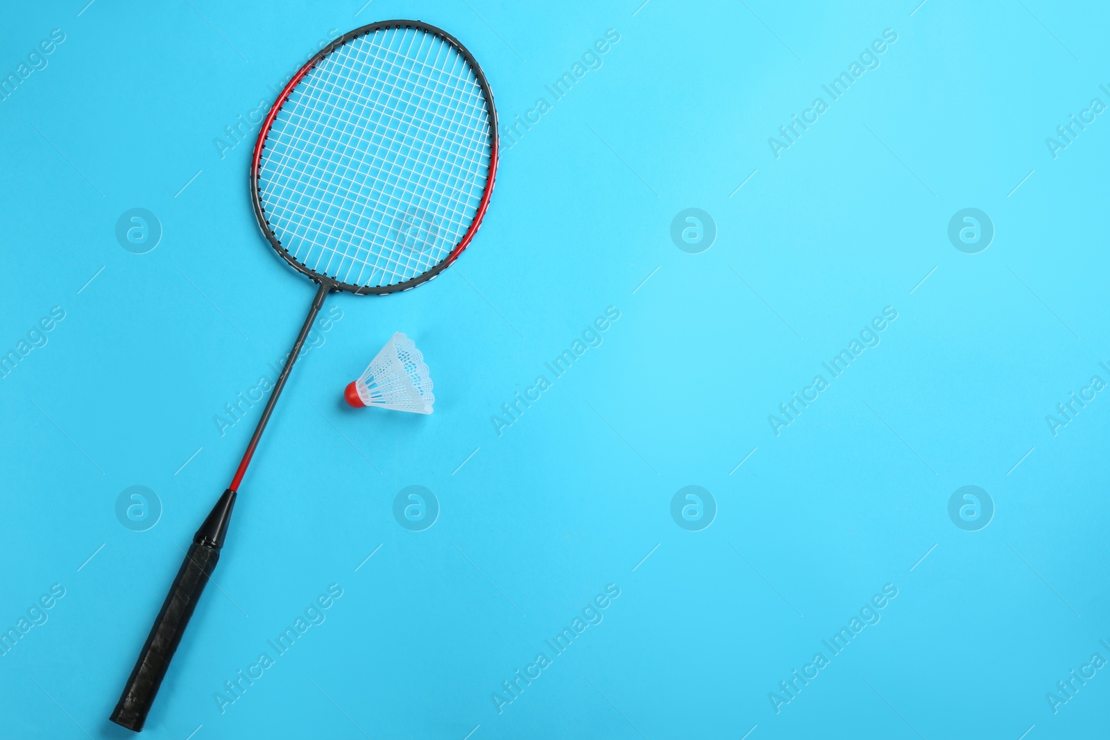 Photo of Racket and shuttlecock on light blue background, flat lay with space for text. Badminton equipment