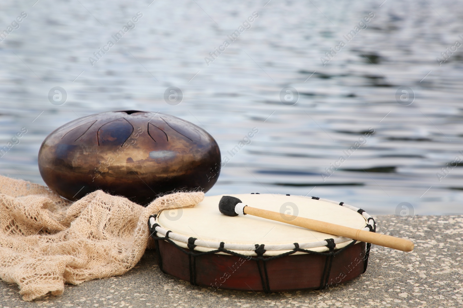 Photo of Different drums and drumstick near sea. Percussion musical instruments