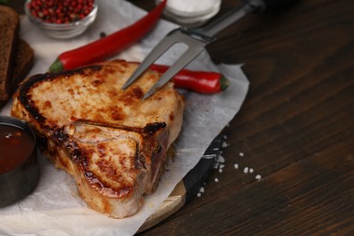 Photo of Tasty grilled meat, marinade, fork and chili on wooden table, closeup. Space for text
