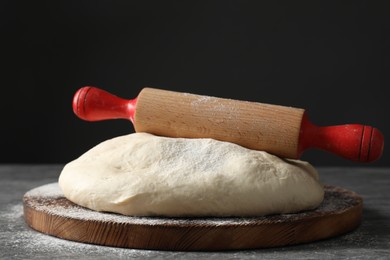 Photo of Raw dough and rolling pin on grey table