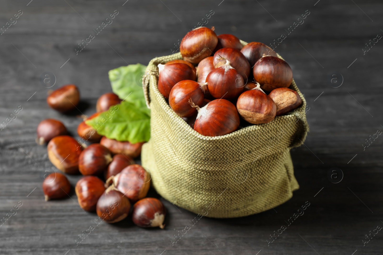 Photo of Fresh sweet edible chestnuts on black wooden table