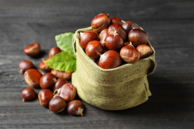 Photo of Fresh sweet edible chestnuts on black wooden table