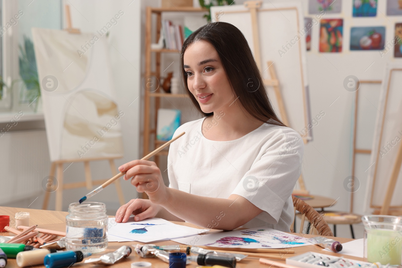 Photo of Beautiful young woman painting in studio. Creative hobby