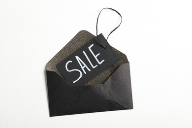 Photo of Tag with word SALE and envelope on white background, top view. Black Friday concept