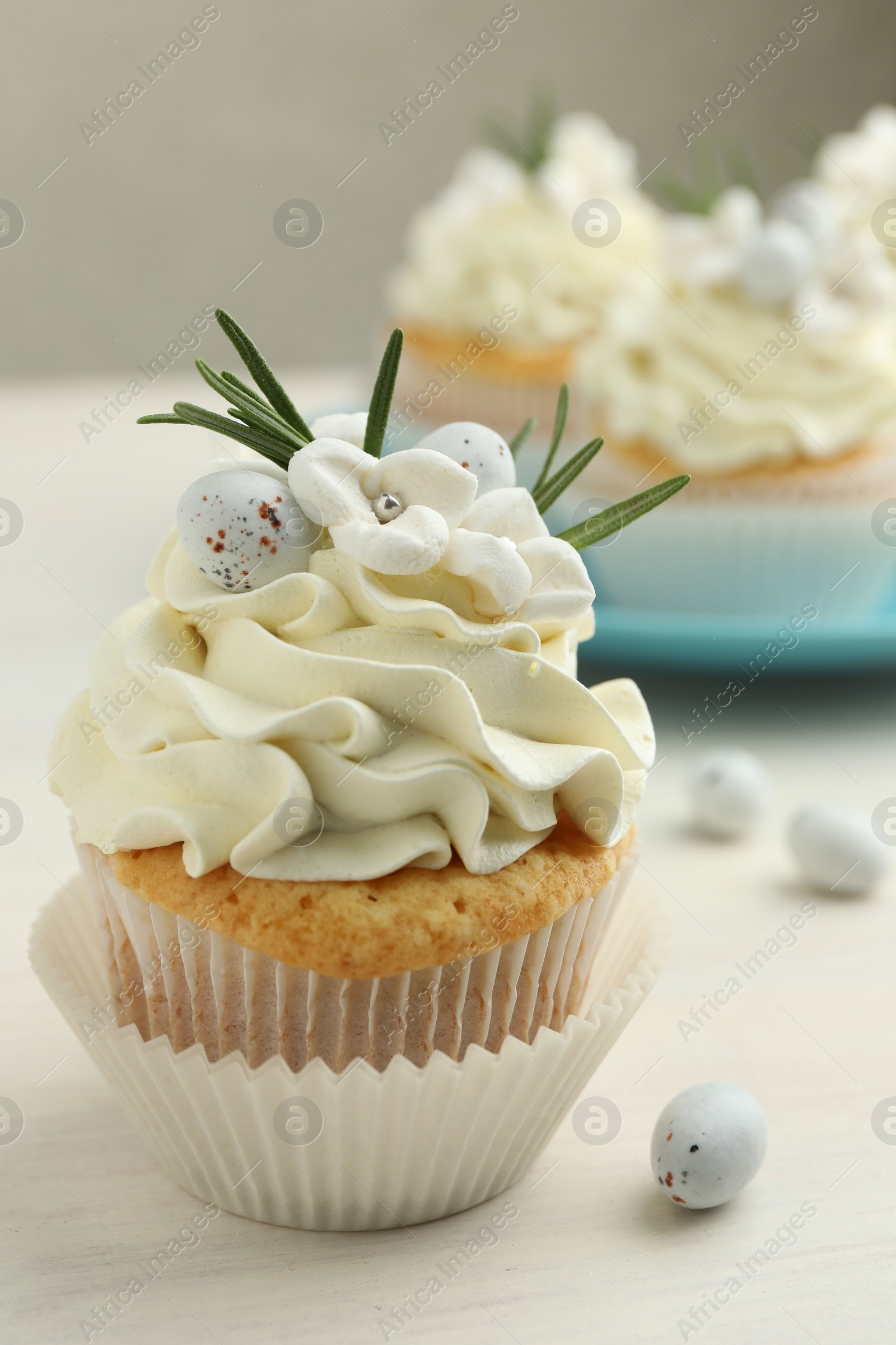 Photo of Tasty Easter cupcake with vanilla cream on light wooden table