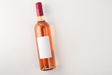 Photo of Bottle of tasty rose wine on white background, top view. Space for text