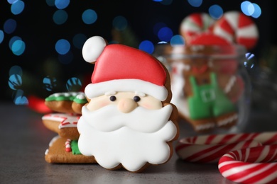 Photo of Decorated Christmas cookies on grey table against blurred festive lights