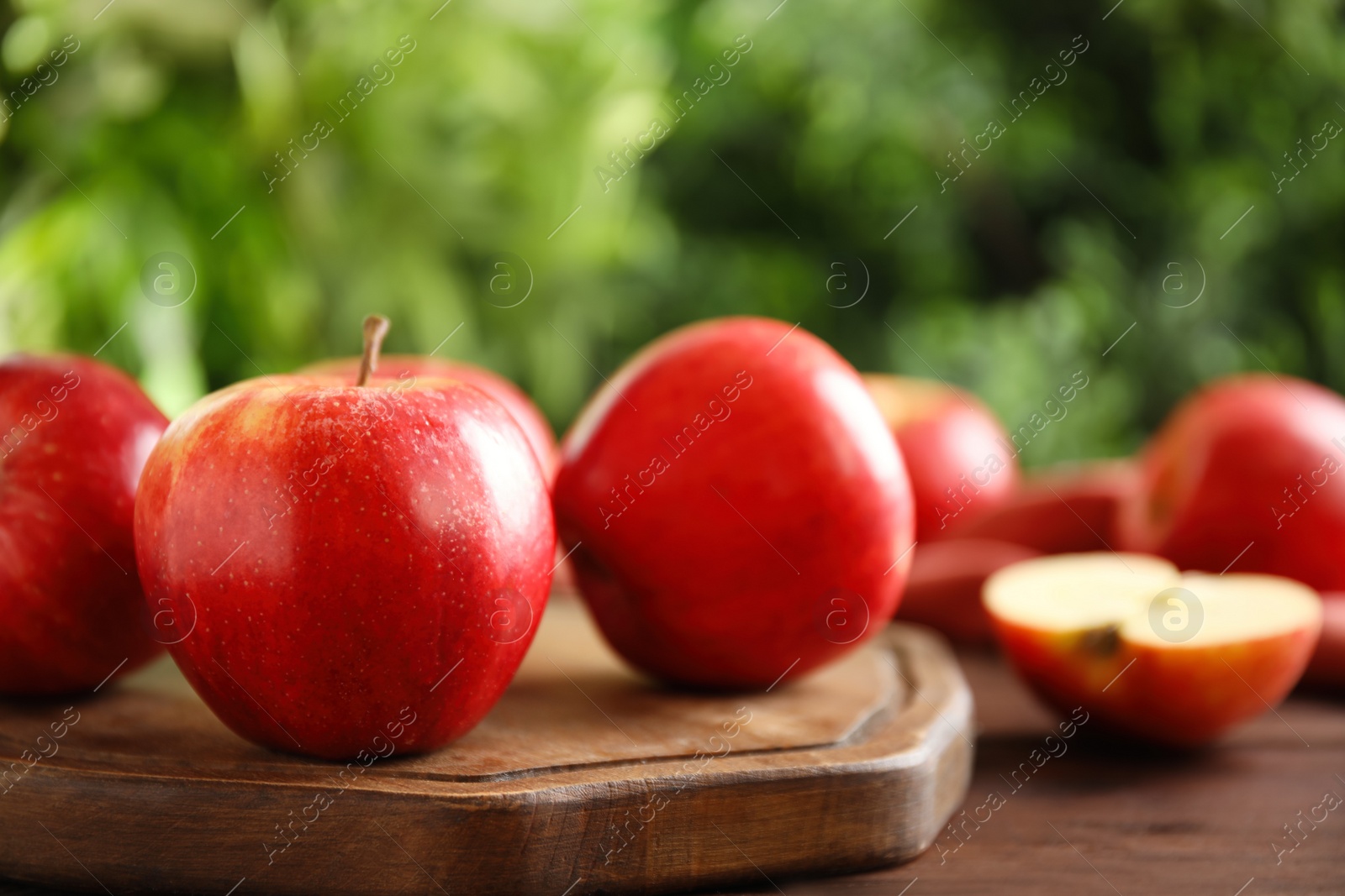 Photo of Fresh ripe red apples on wooden table against blurred background. Space for text