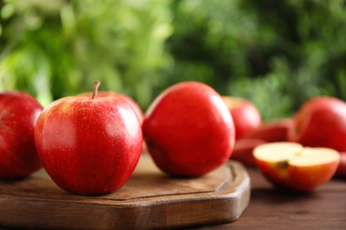Fresh ripe red apples on wooden table against blurred background. Space for text
